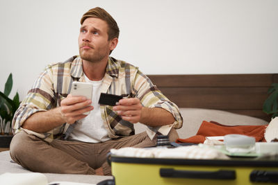 Young man using mobile phone while sitting on sofa at home