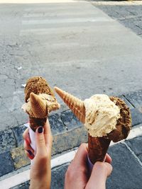 Cropped image of man and woman holding ice creams on street