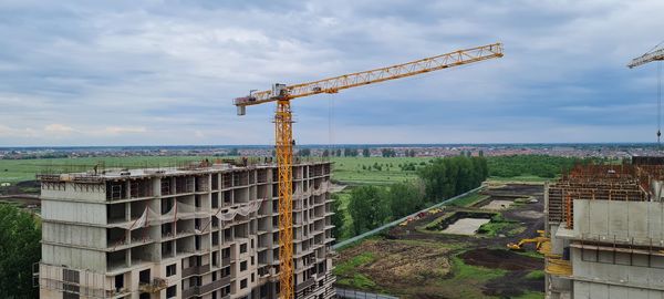 Crane by building against sky in city