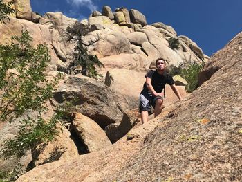 Low angle view of young man standing on mountain