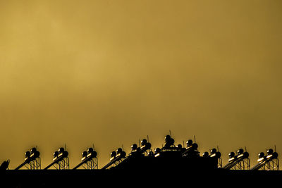 Low angle view of pipes against orange sky during sunset