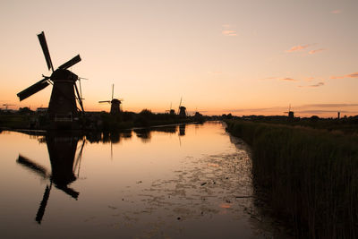 Traditional windmill with reflection against sky during sunset