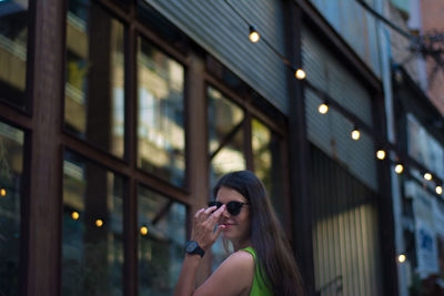 Portrait of woman in sunglasses against illuminated building