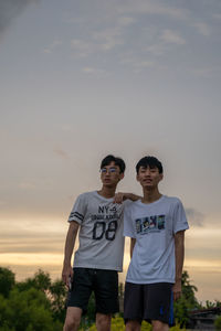 Portrait of young man standing against sky during sunset