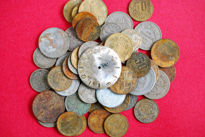 Directly above shot of coins and wristwatch on pink background
