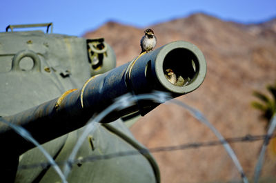 Close-up of old machine part against blue sky