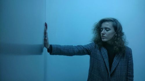 Young woman touching wall and standing