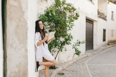 Woman holding umbrella against building