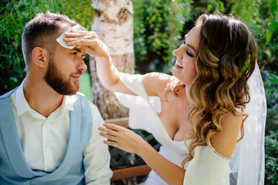 Bride wiping grooms face outdoors