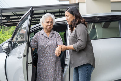 Portrait of smiling friends standing against car