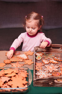 Girl arranging christmas gingerbread cookies in wooden tray at home