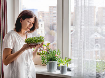 Woman takes care of houseplants and microgreens on windowsill.growing edible food.gardening at home.