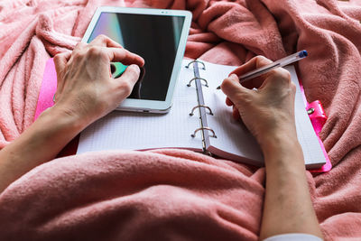 Midsection of woman using mobile phone on bed