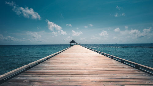 Pier over sea against cloudy sky