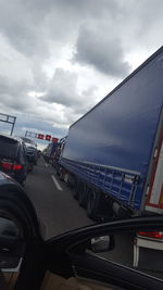 Vehicles on road against sky seen through car windshield