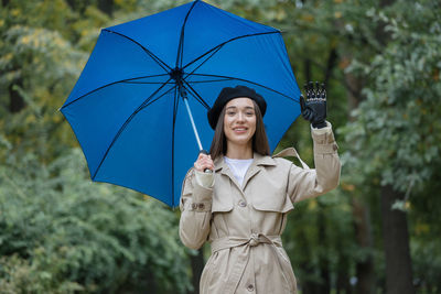 Cyber woman under an umbrella with a bionic prosthesis on her arm is talking on the phone and