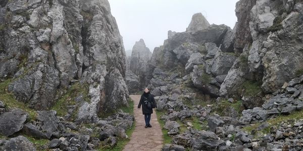 Full length of man standing on rocks against mountain