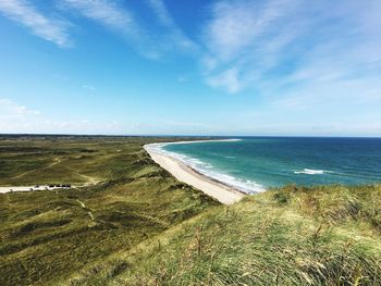 View of calm beach against cloudy sky