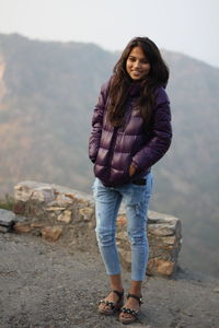 Portrait of young woman standing on rock