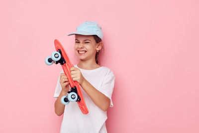 Portrait of smiling young woman holding toy against pink background