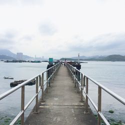 Jetty leading to calm sea against the sky