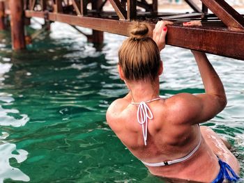 Rear view of woman in bikini swimming pool