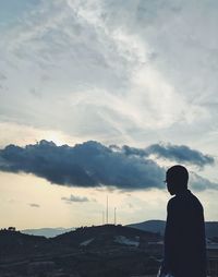 Rear view of silhouette man standing on mountain against sky