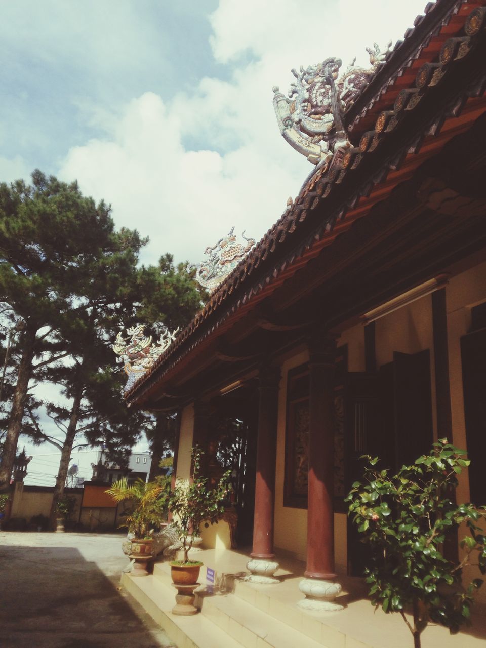 architecture, building exterior, built structure, sky, low angle view, tree, house, cloud - sky, roof, cloud, residential structure, residential building, outdoors, day, place of worship, potted plant, facade, building, no people, religion