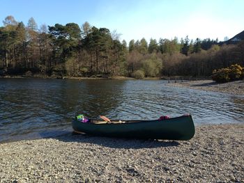 Boat moored on lake against sky