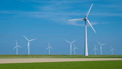 Windmills on field against sky