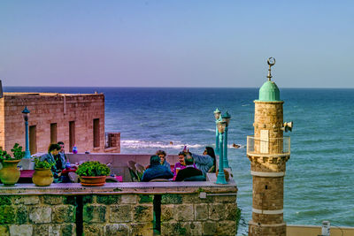 People sitting on beach against clear sky