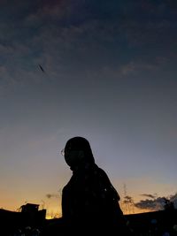 Low angle view of silhouette woman standing against sky during sunset