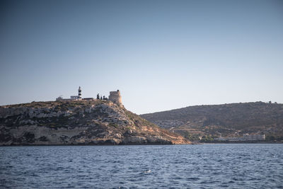 Scenic view of sea by mountain against clear sky