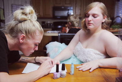 Woman applying nail polish on teenage girl hand at home