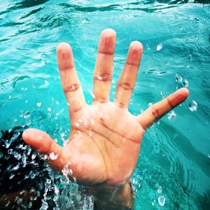 Close-up of hand on water in swimming pool