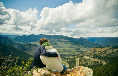 Rear view of man sitting on mountain