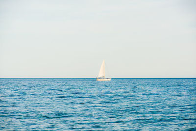 Sailboat sailing on sea against clear sky