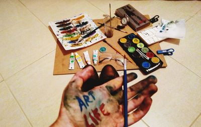 High angle view of hand holding painting on floor