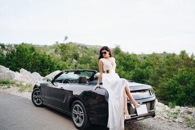 Portrait of woman standing against car