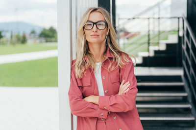 Modern business woman in glasses and a suit stands with her arms crossed