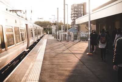 People waiting at railroad station platform in city