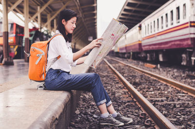 Woman reading map at railroad station platform