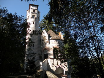 Low angle view of trees and building against sky