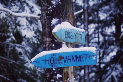 Close-up of signboard against snow covered trees