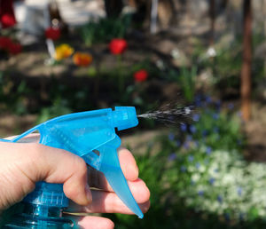 Cropped hand holding spray bottle outdoors