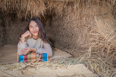 Portrait of young woman lying on mat in hut at village