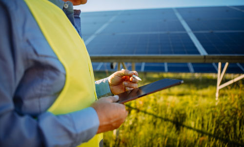 Inspector engineer man holding digital tablet working in solar panels power farm