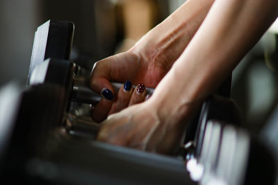 Cropped hands lifting dumbbells at gym