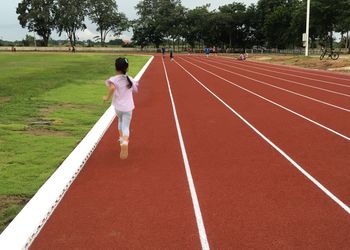 Rear view of girl running on track