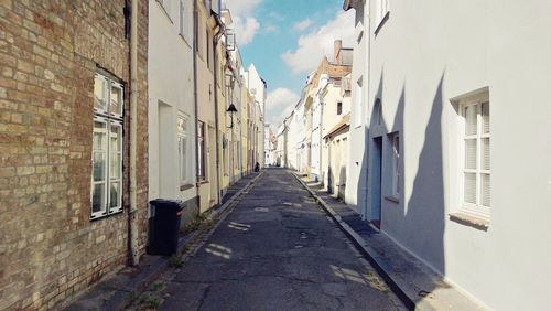 Alley amidst houses against sky